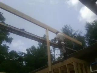 Carpenter setting a ridge beam over a new addition frame — Ice Dam Removal by Roofing Brothers in Hialeah