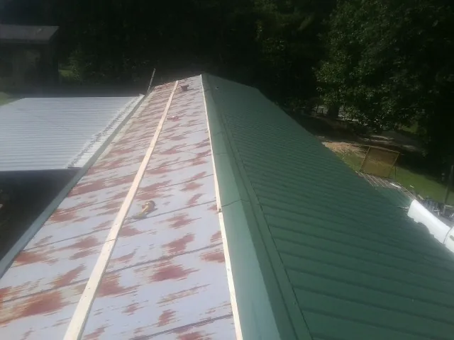 Old rusted panels beside newly installed green metal roofing — Wind Damage Roof Repair by Roofing Brothers in Hialeah