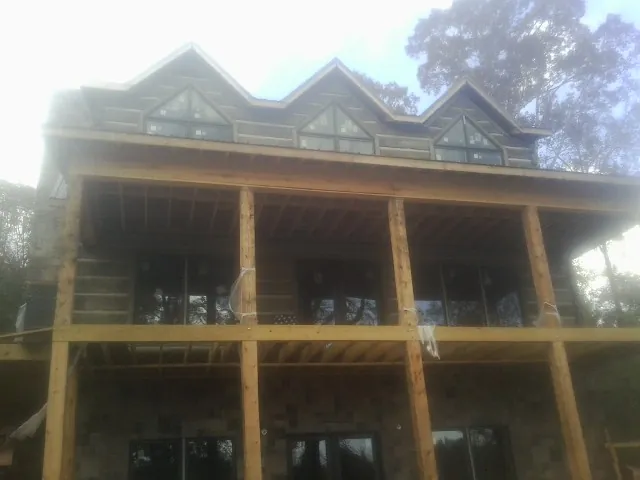 Dormers and porch framing on a large log home under construction — Roof Coating work by our crew in Hialeah