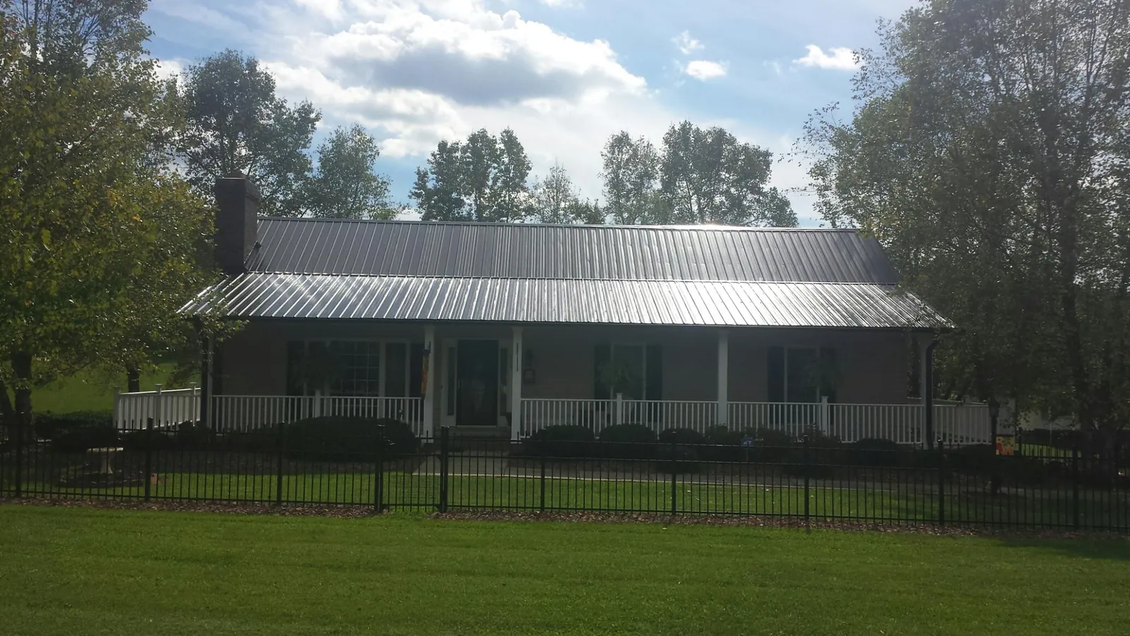 Gray metal roof on a brick ranch with a full width front porch — Gutter Guard Installation work by our crew in Hialeah