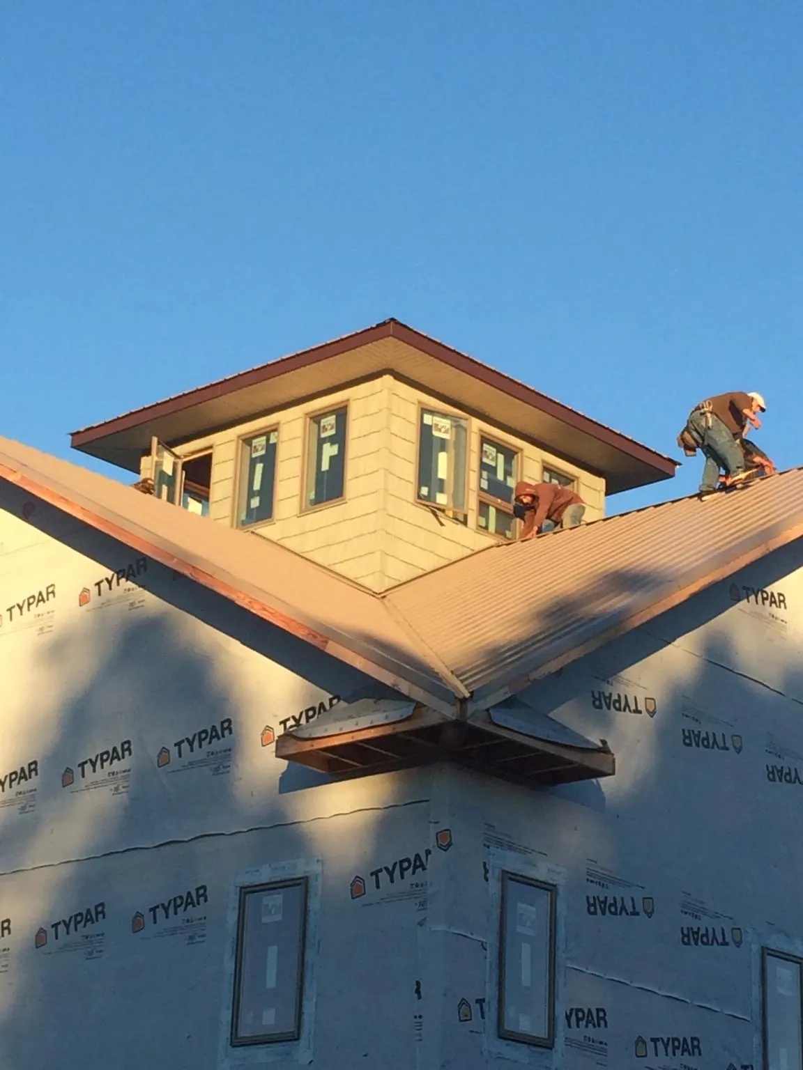 Roofers working around a rooftop cupola on a new metal roof at sunset — Roof Waterproofing in Hialeah by Roofing Brothers